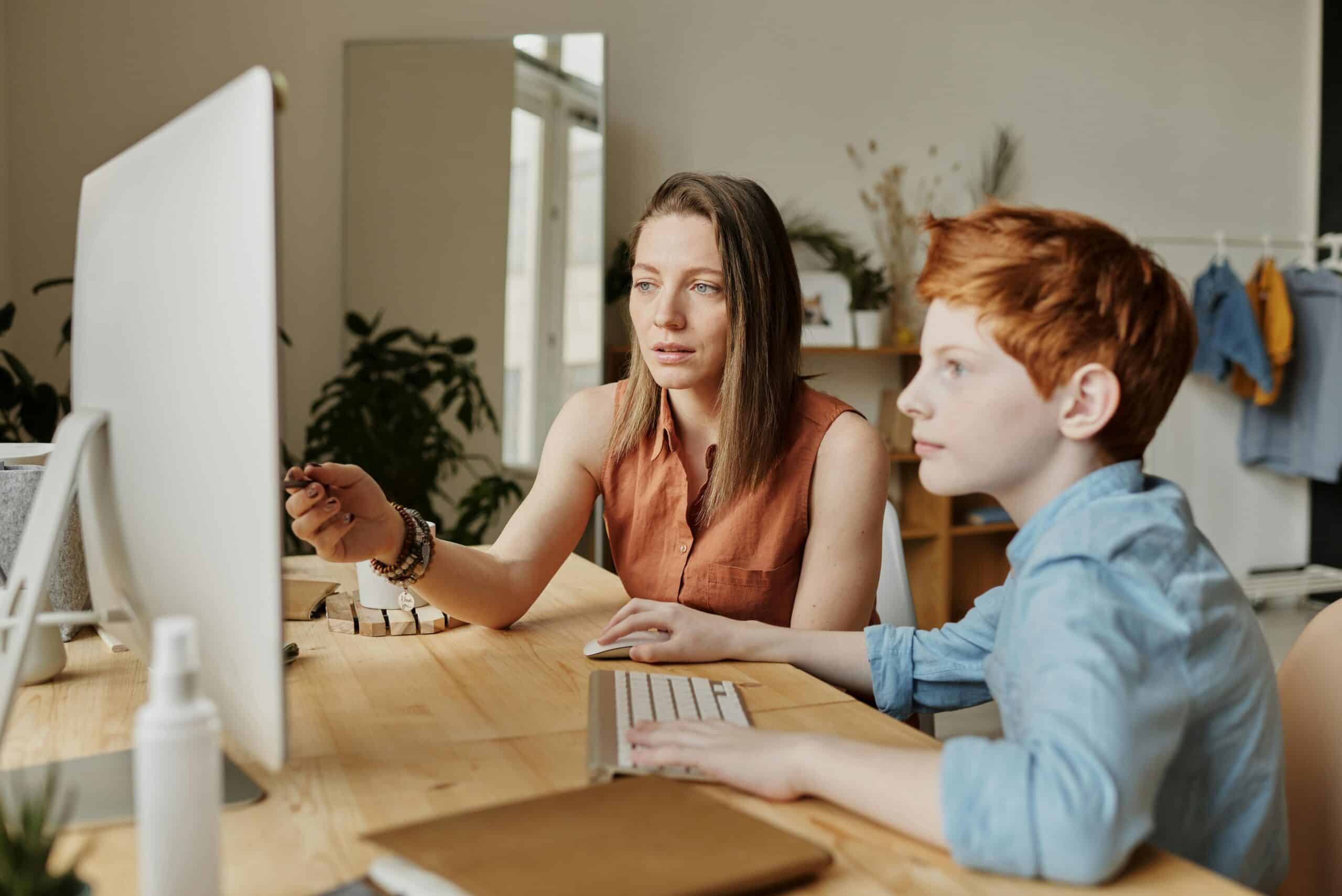 adult and child look at computer screen